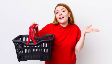 Kızıl saçlı güzel kadın kendini mutlu hissediyor, bir çözüm ya da fikir bulduğuna şaşırıyor. boş alışveriş sepeti kavramı