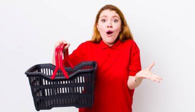 Kızıl saçlı güzel kadın çok şaşırmış ve şok olmuş hissediyor. boş alışveriş sepeti kavramı