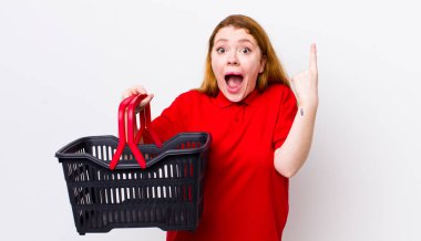 Kızıl saçlı, güzel bir kadın bir fikri fark ettikten sonra mutlu ve heyecanlı bir dahi gibi hissediyor. boş alışveriş sepeti kavramı