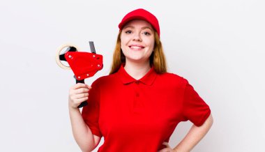 Kızıl saçlı güzel kadın mutlu bir şekilde gülümsüyor, eli kalçasında ve kendinden emin. Packer çalışanı konsepti