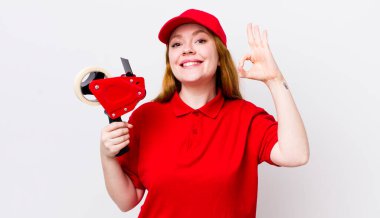 Kızıl saçlı güzel bir kadın kendini mutlu hissediyor. Onayını iyi bir hareketle gösteriyor. Packer çalışanı konsepti