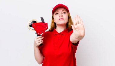 Kızıl saçlı güzel kadın ciddi görünüyor. Avuç içini gösteriyor. Durdurma hareketi yapıyor. Packer çalışanı konsepti