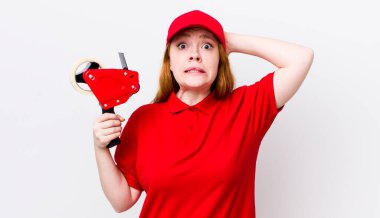 Kızıl saçlı güzel kadın stresli, endişeli ya da korkmuş, elleri başının üstünde. Packer çalışanı konsepti