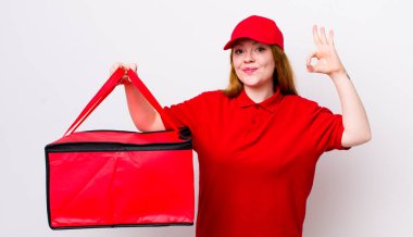 Kızıl saçlı güzel bir kadın kendini mutlu hissediyor. Onayını iyi bir hareketle gösteriyor. Pizza teslimatı kavramı