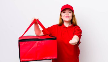 Kızıl saçlı, güzel bir kadın arkadaşça gülümsüyor ve bir konsept sunuyor. Pizza teslimatı kavramı