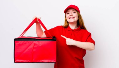 Kızıl saçlı güzel bir kadın neşeyle gülümsüyor, mutlu hissediyor ve bir tarafı işaret ediyor. Pizza teslimatı kavramı