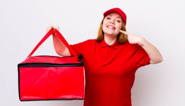 Kızıl saçlı, güzel bir kadın kendi gülüşünü işaret ediyor. Pizza teslimatı kavramı