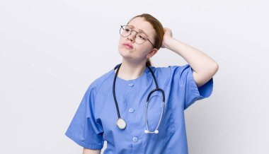 Kızıl saçlı güzel kadın mutlu bir şekilde gülümsüyor ve hayal kuruyor ya da şüphe ediyor. hemşire konsepti