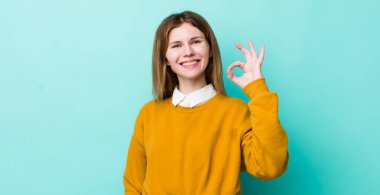 Kızıl saçlı güzel bir kadın mutlu, rahat ve tatmin olmuş hissediyor. Onayını iyi niyet göstergesi olarak gösteriyor.