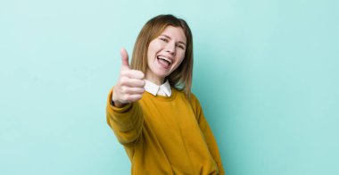 Kızıl saçlı güzel bir kadın gururlu, tasasız, kendinden emin ve mutlu, olumlu gülümsüyor.