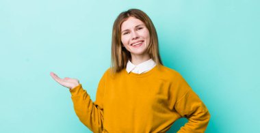 Kızıl saçlı güzel kadın gülümsüyor, kendinden emin, başarılı ve mutlu hissediyor, fotokopi alanında fikir veya konsept gösteriyor.