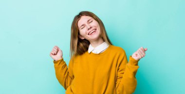 kızıl saçlı güzel kadın gülümsüyor, kaygısız hissediyor, rahat ve mutlu, dans ediyor ve müzik dinliyor, bir partide eğleniyor.