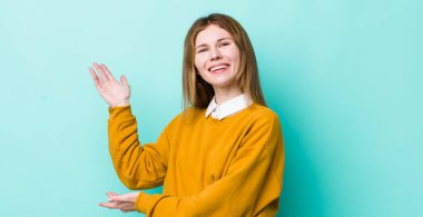 Kızıl saçlı güzel kadın gururla ve kendinden emin bir şekilde gülümsüyor, mutlu ve tatmin olmuş hissediyor ve fotokopi alanında bir konsept gösteriyor.