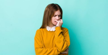 Kızıl saçlı güzel bir kadın ciddi, düşünceli ve endişeli, elleri çenesine bastırılmış, yan bakıyor.