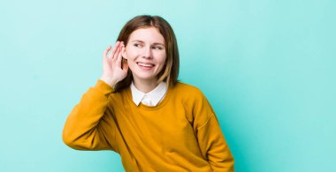 Kızıl saçlı güzel kadın gülümsüyor, tuhaf bir şekilde yan tarafa bakıyor, dedikoduları dinlemeye ya da bir sırrı duymaya çalışıyor.