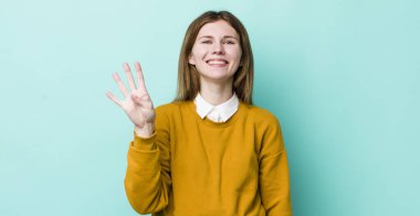 Kızıl saçlı güzel bir kadın gülümsüyor ve arkadaş canlısı görünüyor, dört ya da dört numarayı gösteriyor, eli önde, geri sayıyor.