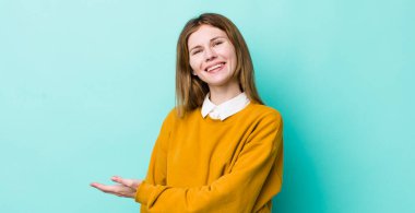 kızıl saçlı güzel bir kadın neşeli bir şekilde gülümsüyor, mutlu hissediyor ve fotokopi alanında bir konsept gösteriyor.