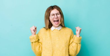 kızıl saçlı güzel kadın çok mutlu ve şaşırmış görünüyor, başarıyı kutluyor, bağırıyor ve zıplıyor.