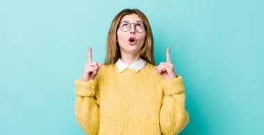 Kızıl saçlı güzel kadın şaşırmış, şaşkın ve ağzı açık görünüyor, iki eliyle uzayı işaret ediyor.
