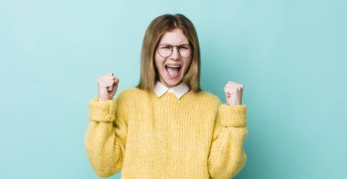 Kızıl saçlı güzel bir kadın mutlu, şaşırmış ve gururlu, bağırıyor ve başarıyı büyük bir gülümsemeyle kutluyor.