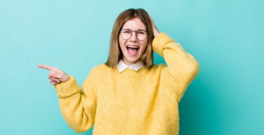 Kızıl saçlı güzel bir kadın gülüyor, mutlu, pozitif ve şaşırmış görünüyor, yanal fotokopi alanını gösteren harika bir fikri fark ediyor.