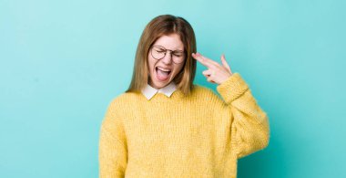 Kızıl saçlı güzel bir kadın mutsuz ve stresli görünüyor, intihar jesti elle silah işareti yapıyor, kafasını işaret ediyor.