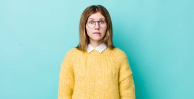 Kızıl saçlı güzel bir kadın kafası karışmış ve kafası karışmış görünüyor. Sinirli bir hareketle dudağını ısırıyor. Sorunun cevabını bilmiyor.