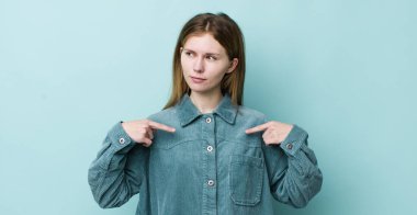 kızıl saçlı güzel bir kadın gururlu, pozitif ve iki eliyle göğsünü gösteren