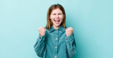 Kızıl saçlı güzel kadın zaferle bağırıyor, gülüyor, mutlu ve heyecanlı hissediyor başarıyı kutlarken.