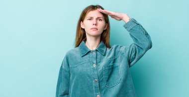 Kızıl saçlı, güzel bir kadın, saygı göstererek, onur ve vatanseverlik adına kameraya selam veriyor.