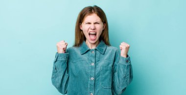 Kızıl saçlı, güzel bir kadın sinirli bir ifadeyle bağırıyor ya da yumruklarıyla başarıyı kutluyor.