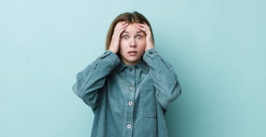 Kızıl saçlı, güzel bir kadın dehşete kapılmış ve şok olmuş hissediyor, ellerini havaya kaldırıyor ve hata yaptığında panikliyor.