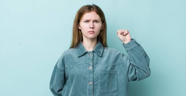 Kızıl saçlı güzel kadın kendini ciddi, güçlü ve asi hissediyor, yumruğunu kaldırıyor, protesto ediyor ya da devrim için savaşıyor.