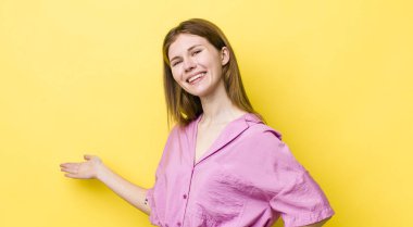 Kızıl saçlı güzel bir kadın mutlu ve neşeli hissediyor, gülümsüyor ve seni hoş karşılıyor, dostça bir jestle içeri davet ediyor.