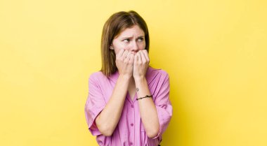 kızıl saçlı güzel kadın endişeli, stresli ve korkmuş görünüyor, tırnaklarını yiyor ve yanal fotokopi alanı arıyor.