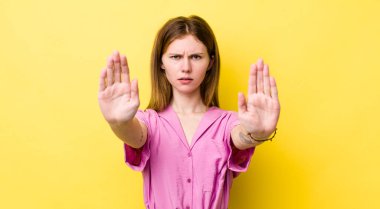 Kızıl saçlı güzel kadın ciddi, mutsuz, kızgın ve hoşnutsuz görünüyor. Girmeyi yasaklıyor ya da her iki avucunun içinde de dur diyor.