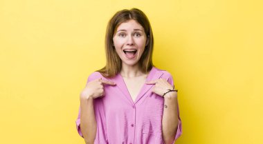 Kızıl saçlı güzel bir kadın mutlu, şaşırmış ve gururlu, heyecanlı, şaşkın bakışlarıyla kendini işaret ediyor.