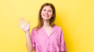 Kızıl saçlı güzel bir kadın gülümsüyor ve arkadaş canlısı görünüyor, 5 ya da 5 numarayı gösteriyor, elleri önde, geri sayıyor.