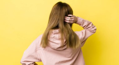 Kızıl saçlı güzel kadın düşünüyor ya da şüphe ediyor, kaşınıyor, kafası karışık ve kafası karışık, arkaya ya da arkaya bakıyor.