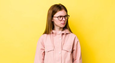 Kızıl saçlı güzel bir kadın üzgün, üzgün ya da kızgın ve olumsuz bir tavır takınıyor, anlaşmazlık içinde kaşlarını çatıyor.