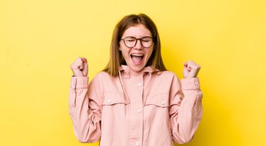 kızıl saçlı güzel kadın çok mutlu ve şaşırmış görünüyor, başarıyı kutluyor, bağırıyor ve zıplıyor.