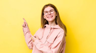 Kızıl saçlı güzel kadın mutlu bir şekilde gülümsüyor ve her iki elinde fotokopi uzayında nesne gösteriyor.