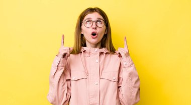 Kızıl saçlı güzel kadın şaşırmış, şaşkın ve ağzı açık görünüyor, iki eliyle uzayı işaret ediyor.