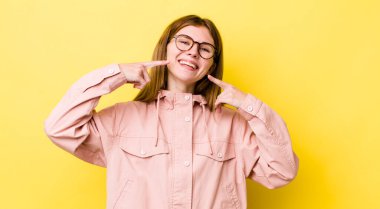 Kızıl saçlı, güzel bir kadın, kendine güvenen, gülümseyen, pozitif, rahat, tatmin olmuş bir tavır sergiliyor.