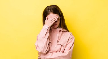 Kızıl saçlı güzel bir kadın stresli, utanmış ya da üzgün görünüyor, baş ağrısı var, yüzünü eliyle kapatıyor.