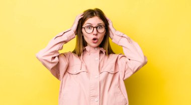 Kızıl saçlı güzel bir kadın heyecanlı ve şaşırmış görünüyor, ağzı açık, iki eli başında, kendini şanslı hissediyor.