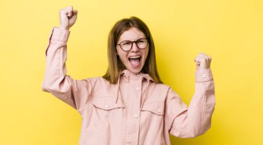 Kızıl saçlı güzel kadın zafer çığlıkları atıyor. Heyecanlı, mutlu ve şaşırmış görünüyor. Kutlama yapıyor.