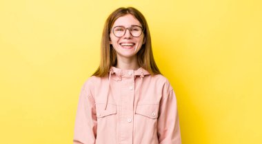 Kızıl saçlı güzel kadın mutlu ve şapşal görünüyor. Geniş, eğlenceli, kaçık bir gülüşü ve açık gözleri var.