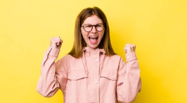 Kızıl saçlı güzel bir kadın mutlu, şaşırmış ve gururlu, bağırıyor ve başarıyı büyük bir gülümsemeyle kutluyor.