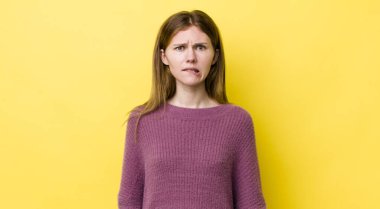 Kızıl saçlı güzel bir kadın kafası karışmış ve kafası karışmış görünüyor. Sinirli bir hareketle dudağını ısırıyor. Sorunun cevabını bilmiyor.